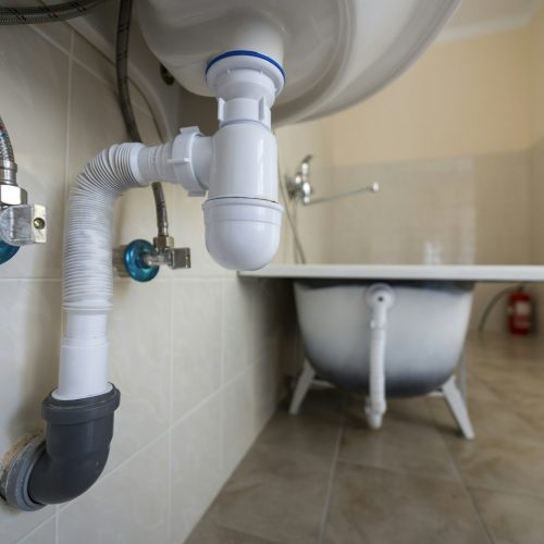 Bottom view of new white washbasin sink connected to sewer