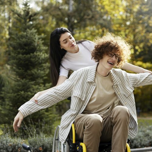Cheerful guy - a disabled person sits in a wheelchair, in the park.
