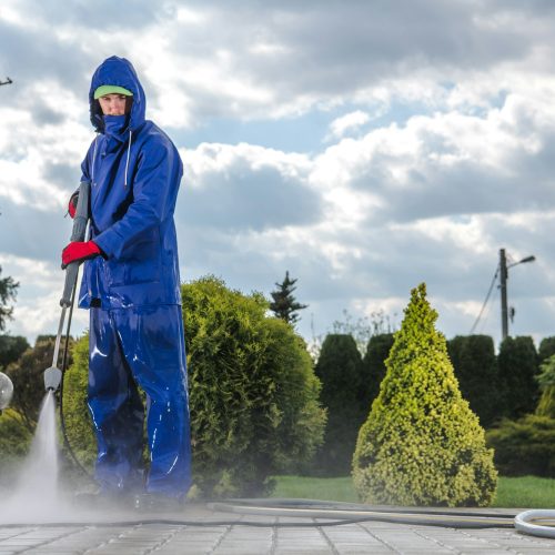 Male Groundkeeper Cleaning Sidewalk With High Pressure Equipment.
