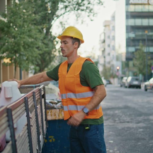 Uniform worker cleaning city. Hardhat urban cleaner in vest throw away rubbish