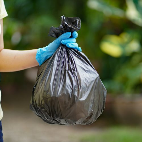 Volunteer charity woman hand holding garbage black bag and plastic bottle garbage