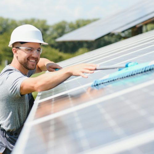 young worker cleaning solar panels.